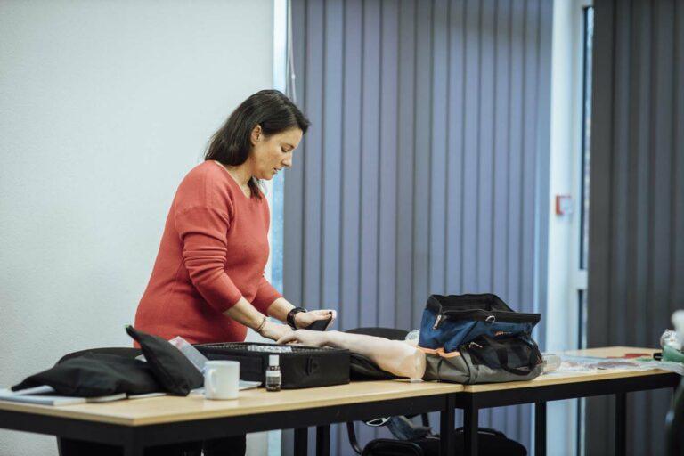 Une femme qui prépare un exercice de secours, un faux bras est visible sur la table