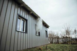 De la fumée sort d'un bâtiment, par une fenêtre