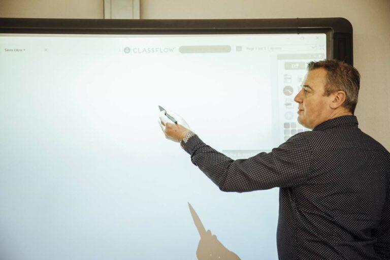 Un homme donne cours et pointe un tableau avec un stylo